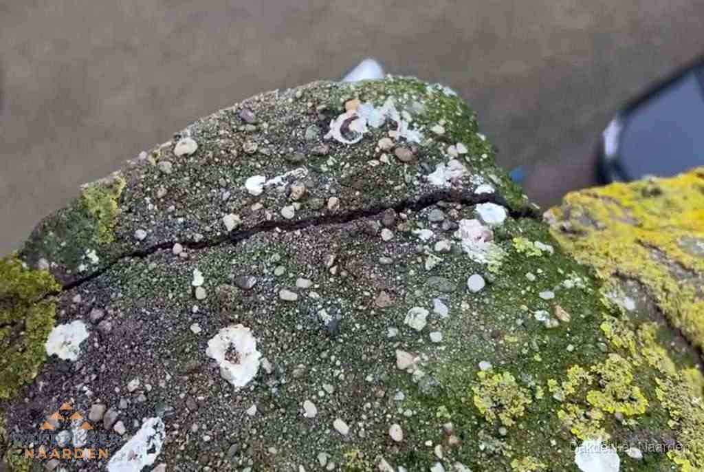 Beschadigde en verweerde nokvorst met scheuren en mos in Naarden